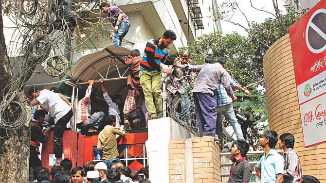 Ignoring the barbed wire on the walls, overseas jobseekers try to get into Probashi Kalyan Bhaban, which houses the expatriate welfare and overseas employment ministry at Eskaton Garden, following a rumour that they have to register for jobs in Saudi Arabia by yesterday. Photo: Sk Enamul Haq 