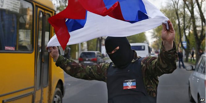 A masked pro-Russia protester waves the Russian flag in Donetsk, eastern Ukraine, on 22 April 2014 Moscow denies being behind the protests and seizures of buildings by pro-Russia militants