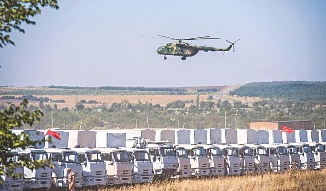 A Russian military helicopter flies over the trucks of Russian humanitarian convoy near Russian-Ukrainian border yesterday.  Photo: AFP