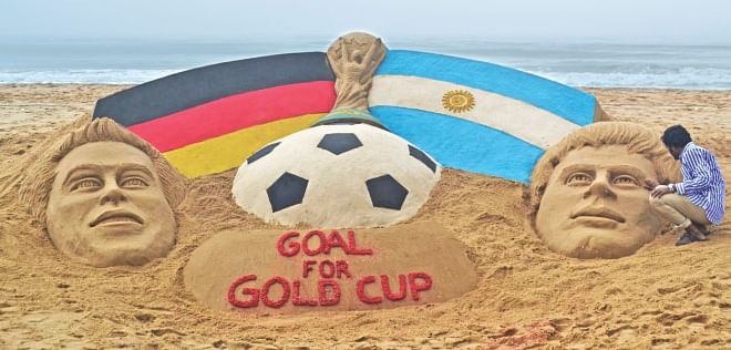 Indian sand artist Sudarshan Pattnaik works on a sand sculpture depicting the World Cup trophy along with Germany captain Philipp Lahm (L) and Argentina captain Lionel Messi on a beach at Puri in the eastern state of Odisha on Saturday. PHOTO: REUTERS