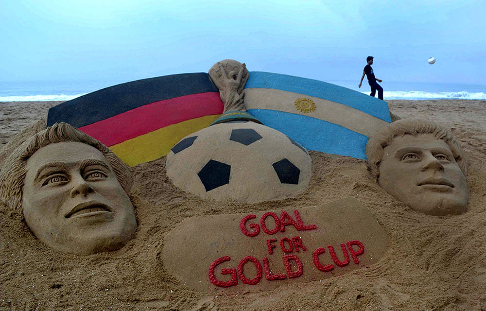 A sand sculpture of the FIFA World Cup trophy between the German (L) and Argentina flags alongside the finalist captains, Germany's Philipp Lahm (L) and Argentina's Lionel Messi with a message 'Goal for Gold Cup' created by Indian sand artist, Sudarsan Pattnaik at Puri beach. Photo: Getty Images