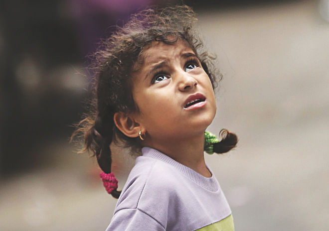 It's not the colour of the sky or the beauty of the clouds. It is sheer terror that impels this little girl to look up as an Israeli drone flies over her home in Gaza City early yesterday. The look in her eyes speaks of the fear and trauma in the lives of Gaza's children, many of whom will endure the scars of war for a lifetime. It is their childhood, their innocence, that is about to be lost. Photo: AFP