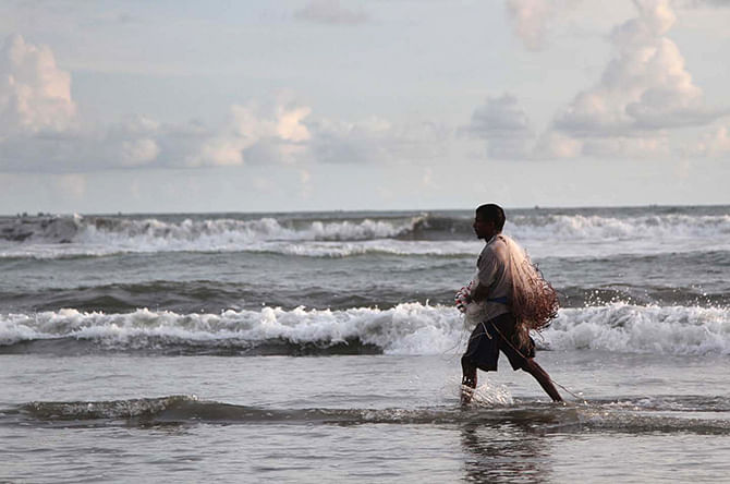 This Star photo taken on July 14, 2014 shows a fisherman on his way to work at Cox’s Bazar sea beach in Chittagong. 