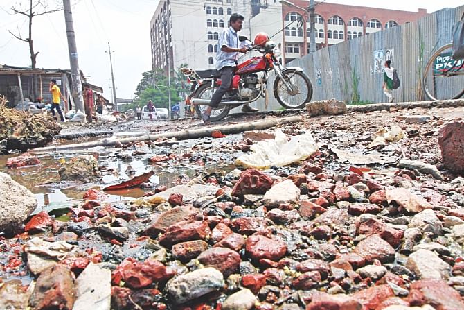 Shahabuddin Sarani in Sher-e-Bangla Nagar in an appalling state where a bike rider tries to negotiate the potholes yesterday. The authorities have turned a blind eye to the repairs of the street. The photo was taken near Islamic Foundation building. Photo: Sk Enamul Haq