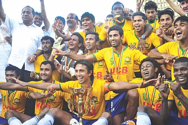 Players and officials of Sheikh Jamal Dhanmondi Club celebrate with the trophy after becoming Bangladesh Premier League champions with two matches in hand at the Bangabandhu National Stadium yesterday. PHOTO: STAR