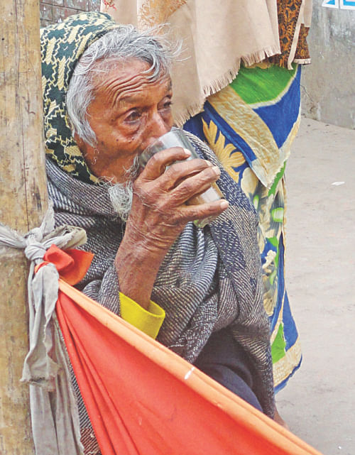 An elderly man takes a drink of tea by the roadside in Dinajpur town.  Photo: Star