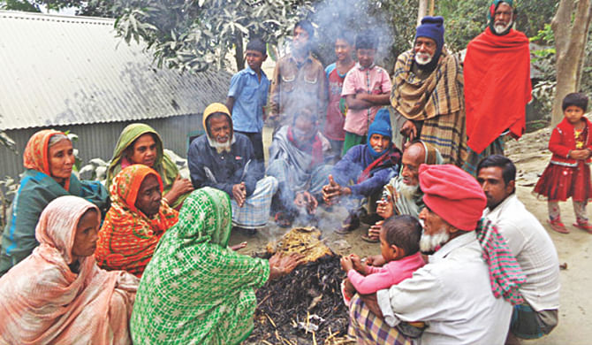 To keep themselves warm, villagers huddle together around a fire in Sariakandi upazila, Bogra. Photo: Star
