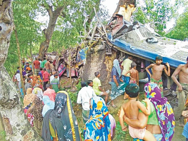 People gather beside the wreckage of a Shohagh Paribahan bus that hit a roadside tree in Jhikorgachha upazila of Jessore yesterday morning. Ten passengers were killed in the accident. Photo: Star