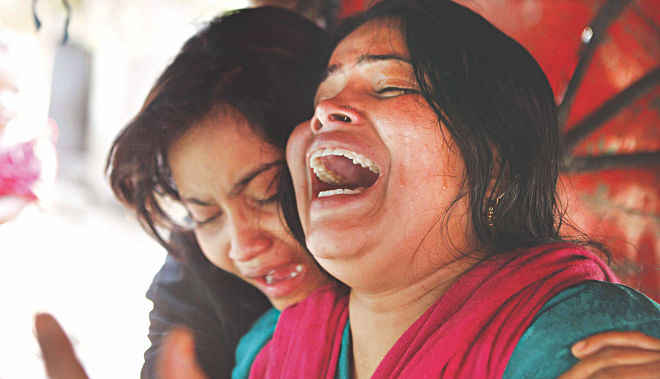 Wife and daughter of Sangram, who was killed in a “crossfire” involving Rab, crying inside a three-wheeler in front of Mitford Hospital in the capital yesterday.  Photo: Rashed Shumon