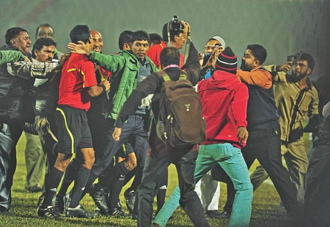 The referee is being escorted to safety by police as a mob charged the official at the end of the feisty encounter.  PHOTOS: STAR