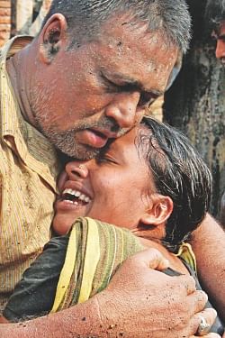 A woman cries her heart out being embraced by her husband after losing literally everything in a fire that swept through a slum area at Jhilpar in the capital's Madhubagh yesterday.  Photo: Anisur Rahman