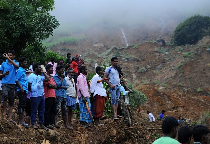 Sri Lankan residents watch search and rescue operations at the site of a landslide caused by heavy monsoon rains in Koslanda village in central Sri Lanka, yesterday. Photo: AFP