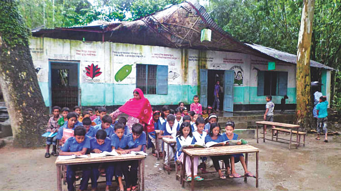 Kids of Bilnothar Government Primary School in Sherpur upazila of Bogra take lessons in the shades of a tree as their schoolhouse, damaged by a storm in May, was yet to be repaired. PHOTO: STAR