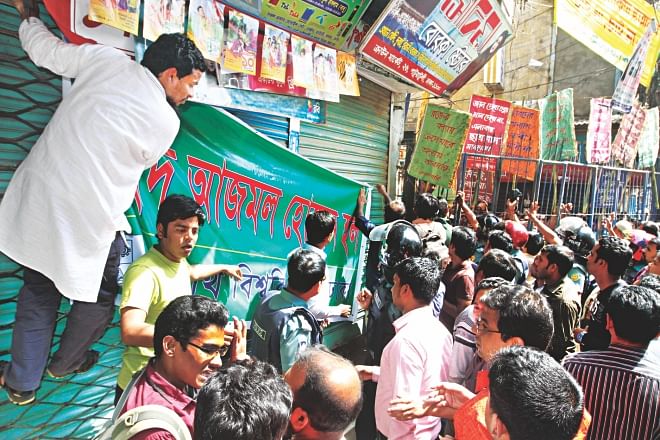 Jagannath University Students hanging a banner reading “Shaheed Azmal Hossain Hall” at Crown Market in Old Dhaka yesterday while locals and traders on the other side of the iron fence demonstrate with placards saying no dormitories will be allowed in the area. Photo: Amran Hossain