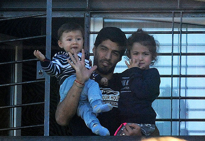 Uruguay's striker Luis Suarez holds his children as he greets fans from his mother's home in Solymar, in the department of Canelones, near Montevideo, on June 27, 2014. Photo: Getty Images 
