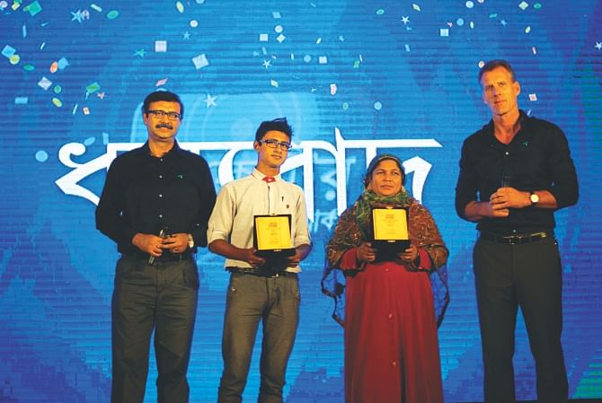 Left, Vivek Sood, chief executive of Grameenphone, and Allan Bonke, chief marketing officer, pose with the company's two subscribers at a celebration in Dhaka yesterday.  Photo: GP