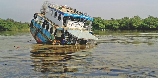 Hit by a cargo vessel, an oil tanker sinking in the Shela river at Joymoni Ghola of the east range of the Sundarbans early yesterday. Photo: Star