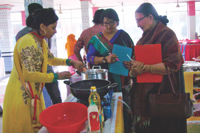 Judges watch a participant prepare her dishes in a cook-off in the Mymensingh round of the Rupchanda-Daily Star Super Chef 2015 at a hotel in the district yesterday. Photo: STAR