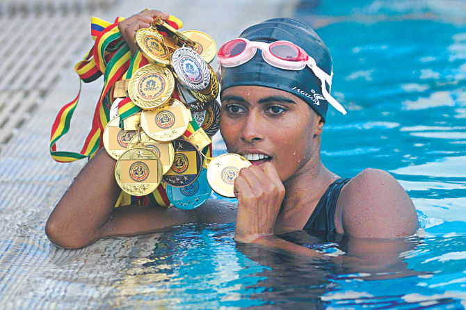 Marium Khatun of Bogra Swimming Centre shows all the 10 gold, three silver and two bronze medals she won during the Cotton Group 30th National Age-Level Swimming Championships at the National Swimming Complex in Mirpur yesterday. PHOTO: STAR