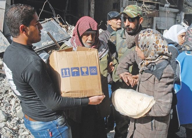 Residents of Syria's besieged Yarmuk Palestinian refugee camp, south of Damascus, receive UN food parcels yesterday. A food convoy gained entry to the Yarmuk refugee camp, where dozens have died from shortages of food and medicines, the UN and Syrian state media said. Photo: AFP
