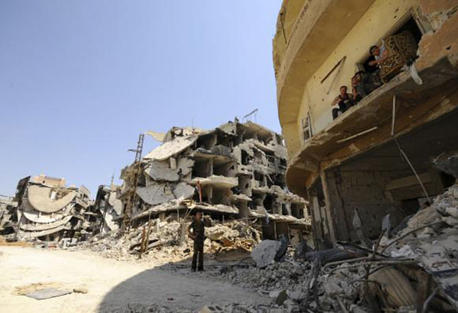 A Syrian army soldier loyal to Syria's President Bashar al-Assad chats with fellow fighters sitting on a balcony of a damaged building in Mleiha, which lies on the edge of the eastern Ghouta region near Damascus airport, after taking control of the area from rebel fighters August 15, 2014. Photo: Reuters  