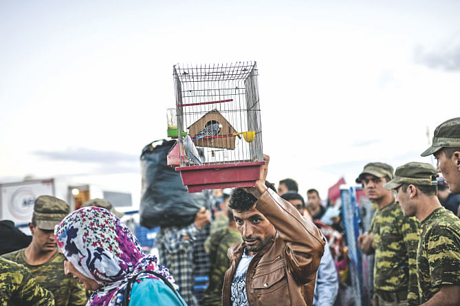 A man carries a bird in a cage as Syrian Kurdish people arrive at the border between Syria and Turkey after several mortars hit both side in the southeastern town of Suruc, in the Sanliurfa province on Monday. Photo: AFP