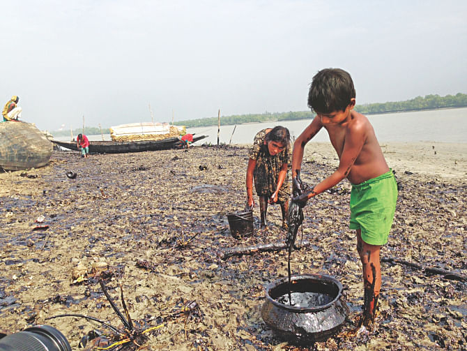 Two children collecting oil on the Shela river in the Sundarbans yesterday close to where tanker Southern Star-7 went down on Tuesday, spilling oil in the eco-sensitive area.  Photo: Pinaki Roy