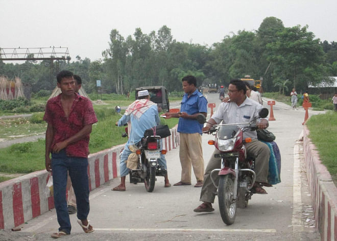 Brokers allegedly engaged by some ruling party men collect toll from vehicles crossing Teesta road bridge in Lalmonirhat Sadar upazila. Photo shows a village cop taking money from a bike rider on the bridge. Photo: Star