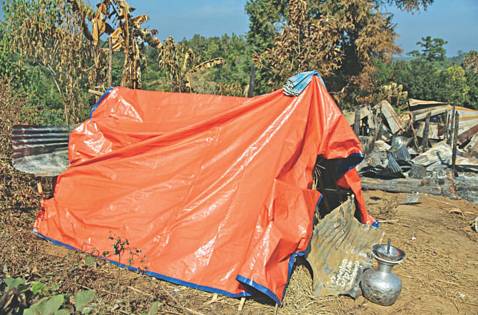 A family builds a tent with a tarpaulin sheet next to their razed home in Suridaspara of Naniarchhar of Rangamati after Bangalee settlers torched 57 homes of the indigenous people on Tuesday. Photo: Star