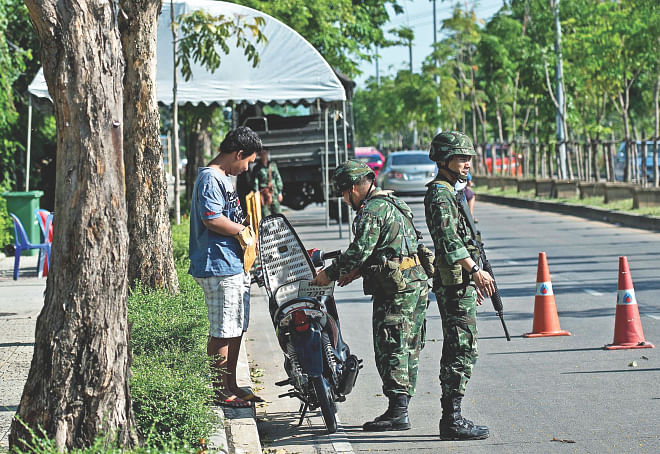 Thai soldiers inspect a motorist at a checkpoint near the pro-government ''Red shirts'' camp site on the outskirts of Bangkok, yesterday.  Photo: AFP