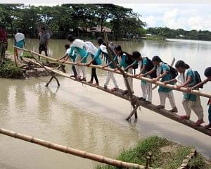 Schoolgirls crossing the collapsed portion of a road through a bamboo bridge. Photo: Star