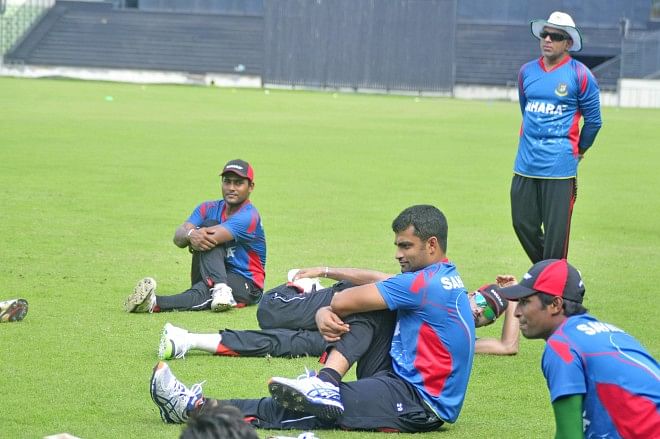 Bangladesh cricketers stretch during their last practice session before Eid ahead of the West Indies tour as coach Chandika Hathurusingha (R) looks on at the Sher-e-Bangla National Stadium in Mirpur yesterday. PHOTO: STAR