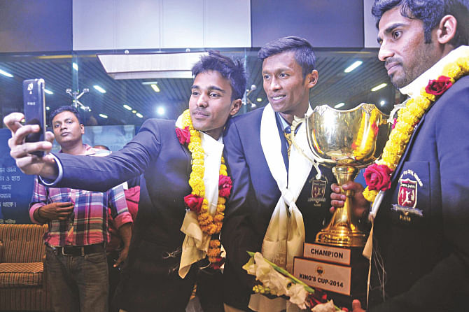 Toklish Ahmed takes a selfie with Yeasin Khan (M) and Shakhawat Hossain Rony, holding the King's Cup trophy, at the VIP Lounge of Hazrat Shahjalal International Airport upon their return from Bhutan last night. PHOTO: FIROZ AHMED