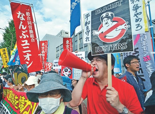Protestors hold placards and shout anti Abe government slogans during a rally in front of the prime minister's official residence in Tokyo, yesterday. Photo: AFP