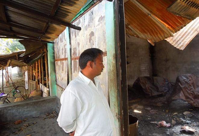 Trader Binod Kumar Roy gives a bleak look at his warehouse torched by Jamaat-Shibir men at Beltoli Bazar in Nilphamari district on the night of December 12 last year in reaction to the execution of Jamaat leader Abdul Quader Mollah. Photo: Star