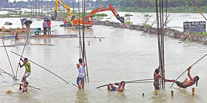 A LAUGHABLE EFFORT … A few workers try to wiggle iron rods while two small diggers find it difficult to reach the illegal wall an encroacher built in the river Turag. Such was the poor effort the BIWTA offered to recover the river near Kamarpara Bridge yesterday. The authorities did nothing while the occupier was building the structures.  Photo: Rashed Shumon