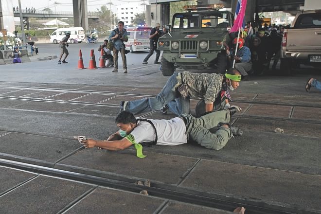 A Thai anti-government protester aims his gun and shoot towards. Thai pro-election protesters (not seen) during clashes in Bangkok, yesterday.   Photo: AFP
