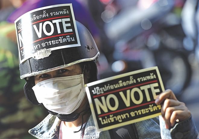 A protester holds a protest placard urging not to vote. Photo: AFP