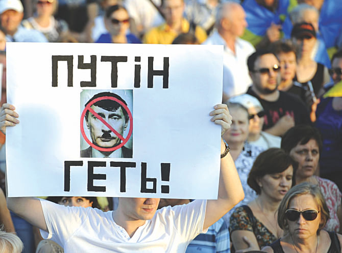 A Ukrainian man holds a placard reading 'Putin get out!' during a rally in the center of the southern Ukrainian city of Mariupol, yesterday. Photo: AFP