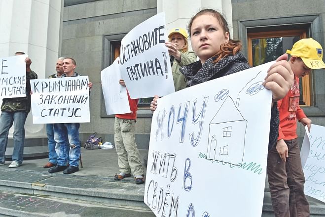 Refugees from Crimea and eastern Ukrainian regions hold placards reading (L-R)  Stop Putin!, I want to live in my house!, ‘Legal status for Crimean’ during a rally to demand a legal legislation of their status in front of the Ukrainian parliament in Kiev yesterday. Photo: AFP