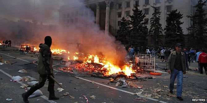 A protester walks past a burning pro-Russian tent camp near the trade union building in Odessa - 2 May 2014 Reports suggest that both pro-Russians and supporters of Kiev were throwing petrol bombs in the area