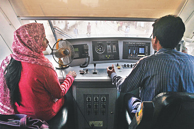 Umme Salma Siddiqa assisting the driver of a shuttle train that runs between the Chittagong Railway Station and the Chittagong University Railway Station. Women are now trying to become train drivers, a job that has been dominated by men for decades.   Photo: Star