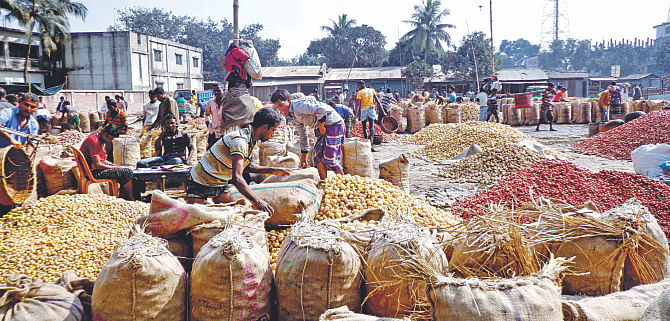 Vegetable farmers sit around their pile of produce at the Mahasthangarh wholesale market in Bogra yesterday with hardly any customers. With seemingly no end to the nationwide blockade, wholesale traders are reluctant in buying perishables which they may not be able to ship.  Photo: Star