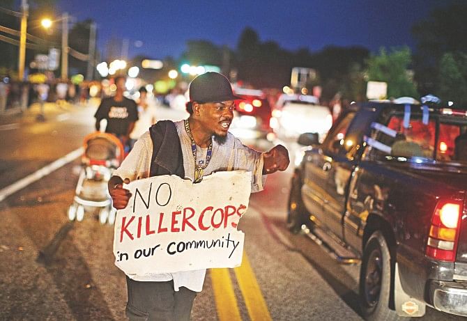 A semonstrator hold a placard to protest the shooting death of Michael Brown Ferguson, Missouri, on Thursday. Violent protests have erupted along West Florissant in Ferguson each of the last four nights as demonstrators express outrage over the shooting death of Michael Brown by a Ferguson police officer on August 9.  Photo: AFP