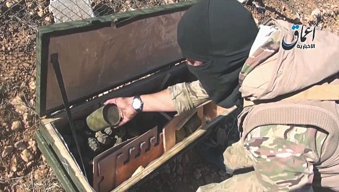 an ISIS militant allegedly displaying the content of a US crate carrying grenades . Photo: AFP