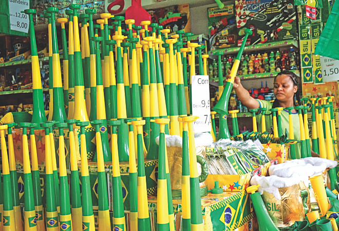 A football fan checks a 'vuvuzela' painted in Brazilian colours at a shop in Belo Horizonte yesterday, on the eve of the World Cup semifinal between Brazil and Germany. PHOTO: AFP