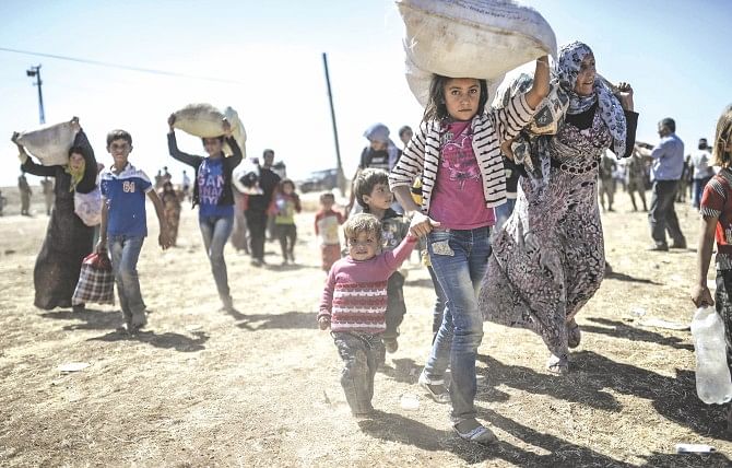 Syrian Kurds carry their belongings after they crossed the border between Syria and Turkey, yesterday. Several thousand Syrian Kurds began crossing into Turkey on Friday fleeing Islamic State fighters who advanced into their villages, prompting warnings of massacres from Kurdish leaders.  Photo: AFP
