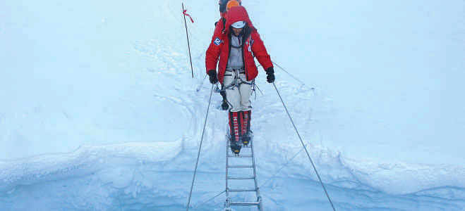 Wasfia crossing a dreadful ladder over a crevasse in Everest. Photo: Chris Klinke