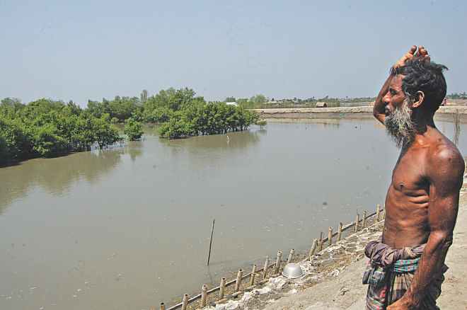 Sirajul Gazi looking at the site where his home used to be before Aila made a landfall in 2009. Now the place goes under water during high tide of the Kobadak river. Photo: Pinaki Roy