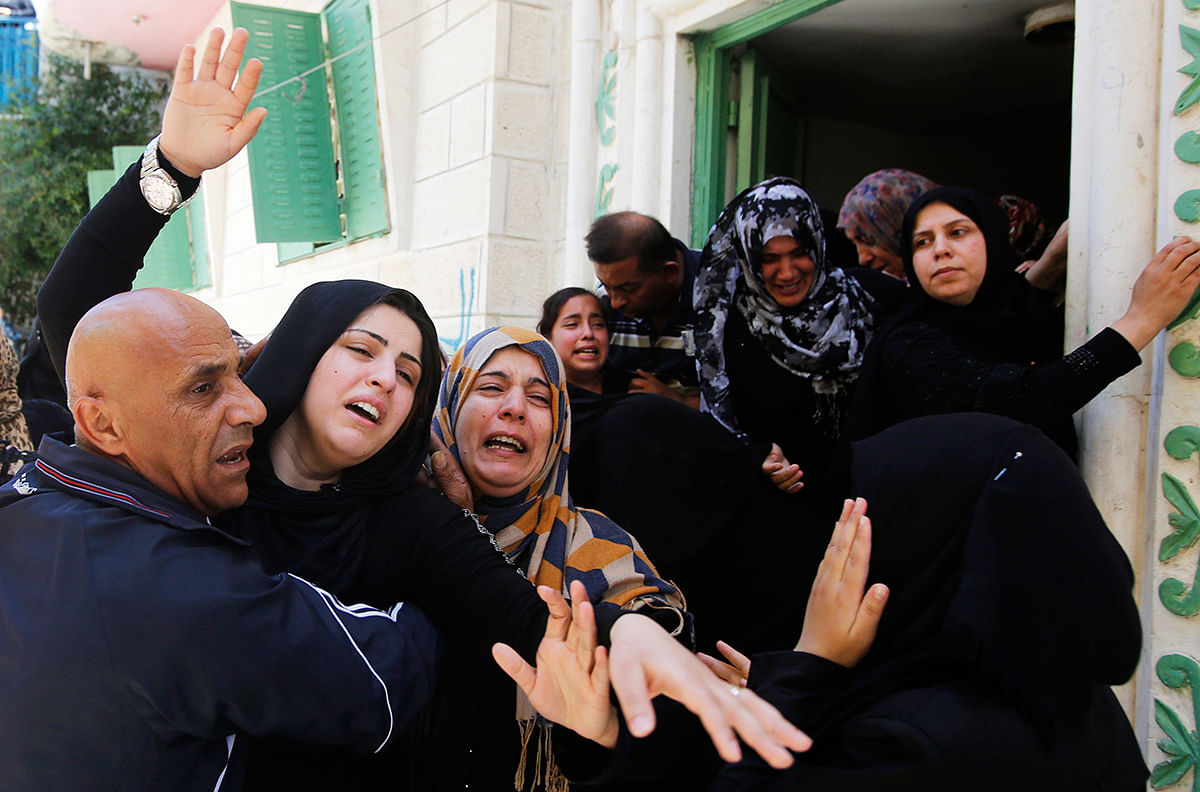 The wife (L) of Palestinian Eid Rabah Fdilat, whom medics said was killed during clashes with Israeli troops on Friday, mourns during his funeral in Arroub refugee camp, north of the West Bank city of Hebron July 26, 2014. Photo: Reuters